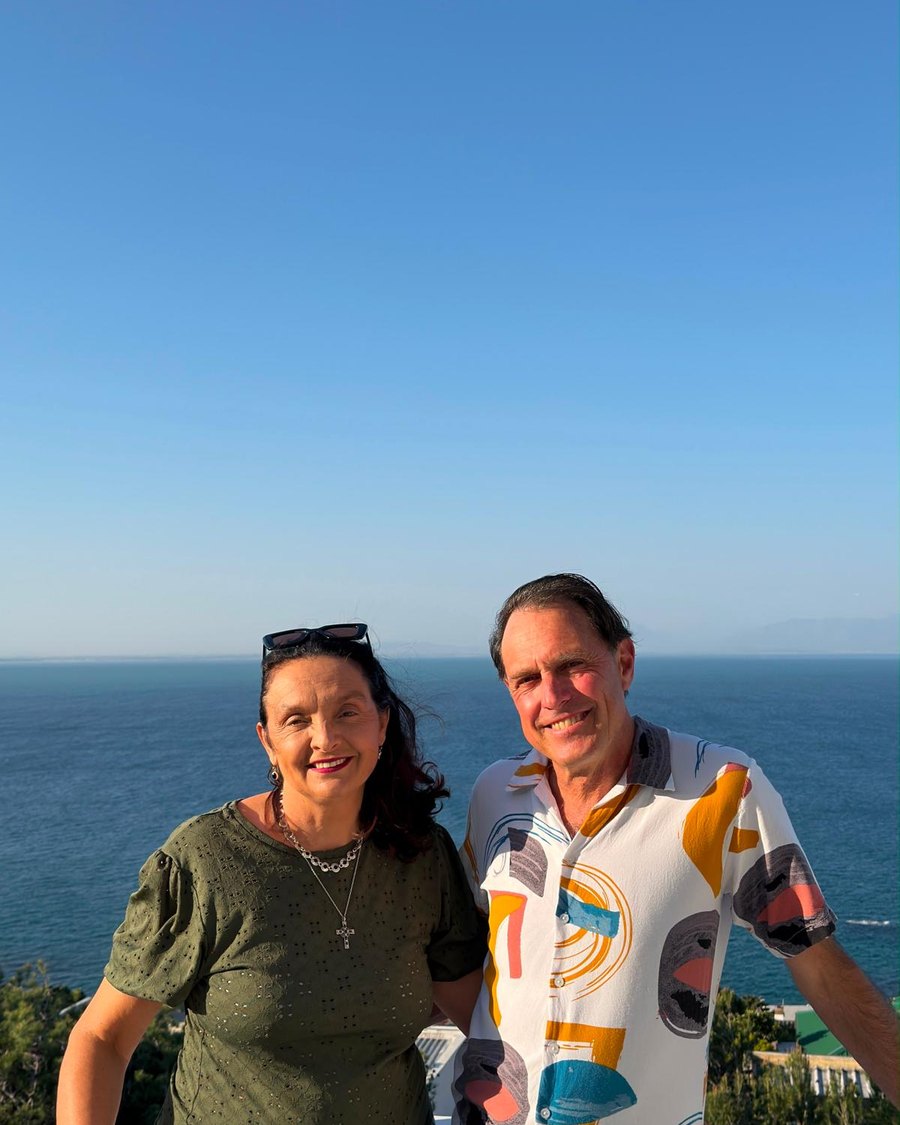 Brett and Brigitta, who run Cape Cat Hotel, with False Bay behind them